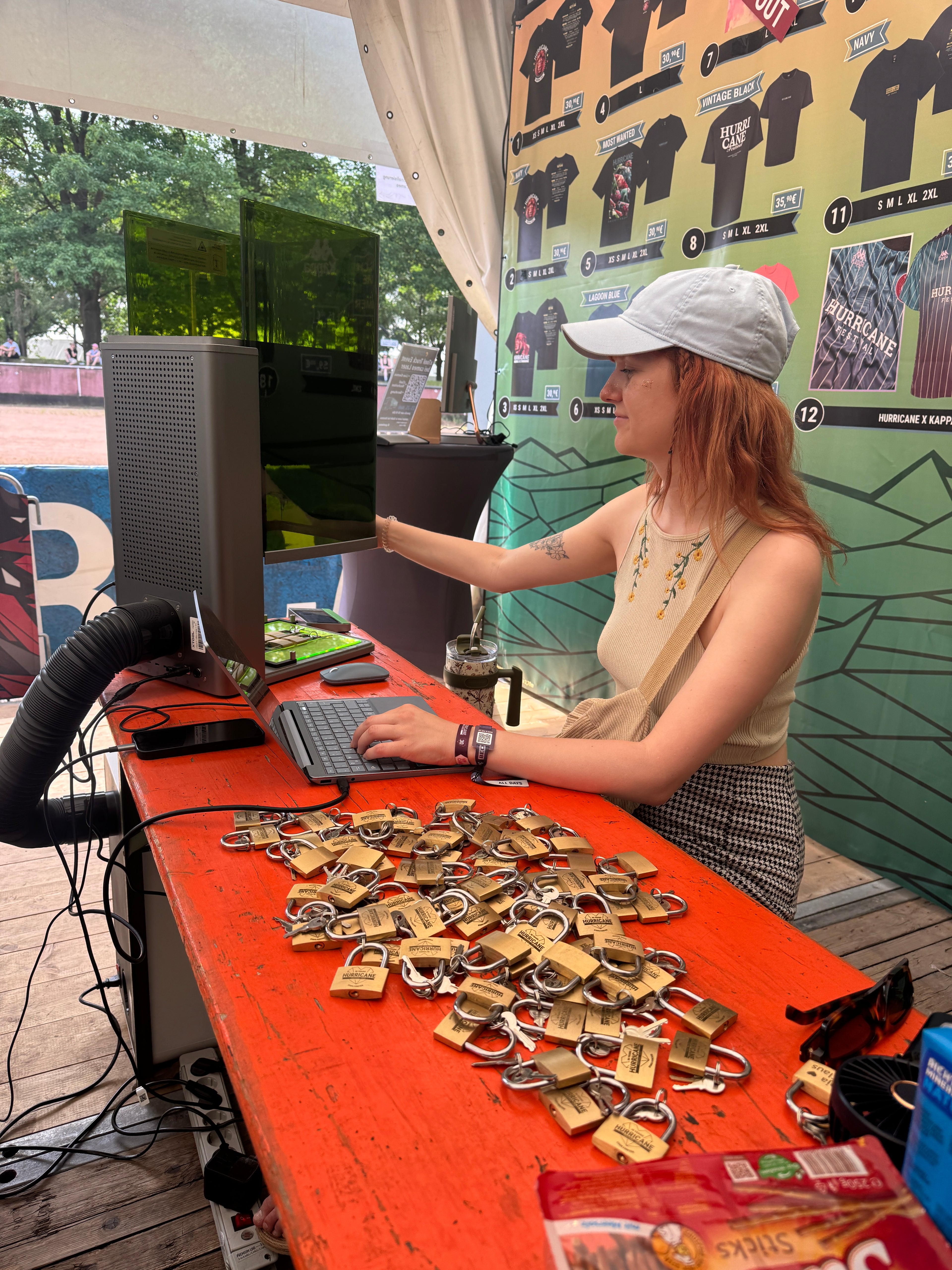 Eine Mitarbeiterin von Cameo graviert am Merch-Stand auf dem Hurricane Festival Schlösser für die Festivalbesucher.