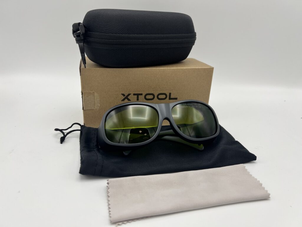 Lieferumfang der xTool Laserschutzbrille mit Schutzetui, Beutel und Reinigungstuch.
